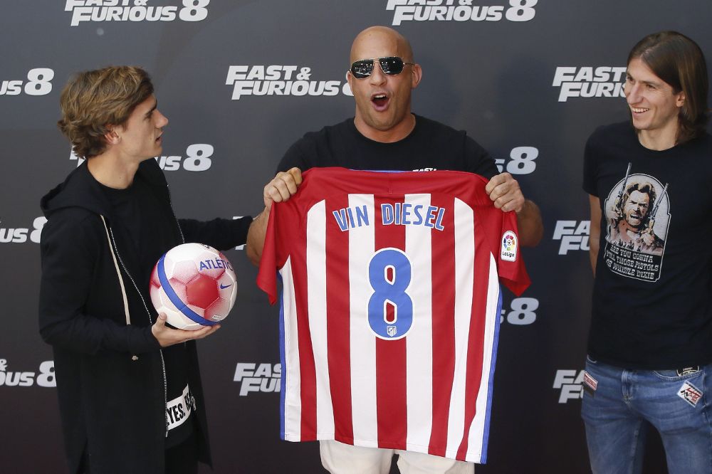 El actor estadounidense Vin Diesel (c) posa con una camiseta del Atlético de Madrid con su nombre, junto al delantero francés de este equipo Antoine Griezmann (i) y el lateral brasileño Filipe Luis (d), durante un acto de promoción de la película 'Fast&Furious 8', en Madrid.