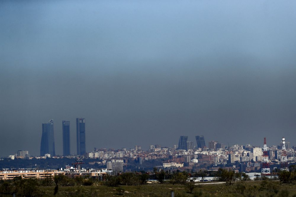 Vista de Madrid con el parque empresarial de las Cuatro Torres (i), en el Paseo de la Castellana de Madrid, y las Torres Kio (d), cubiertas por la 'boina' de contaminacións.