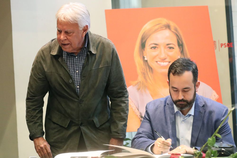 El expresidente del Gobierno, Felipe González (i), firma en el libro de condolencias en la sede del PSOE, en Madrid.