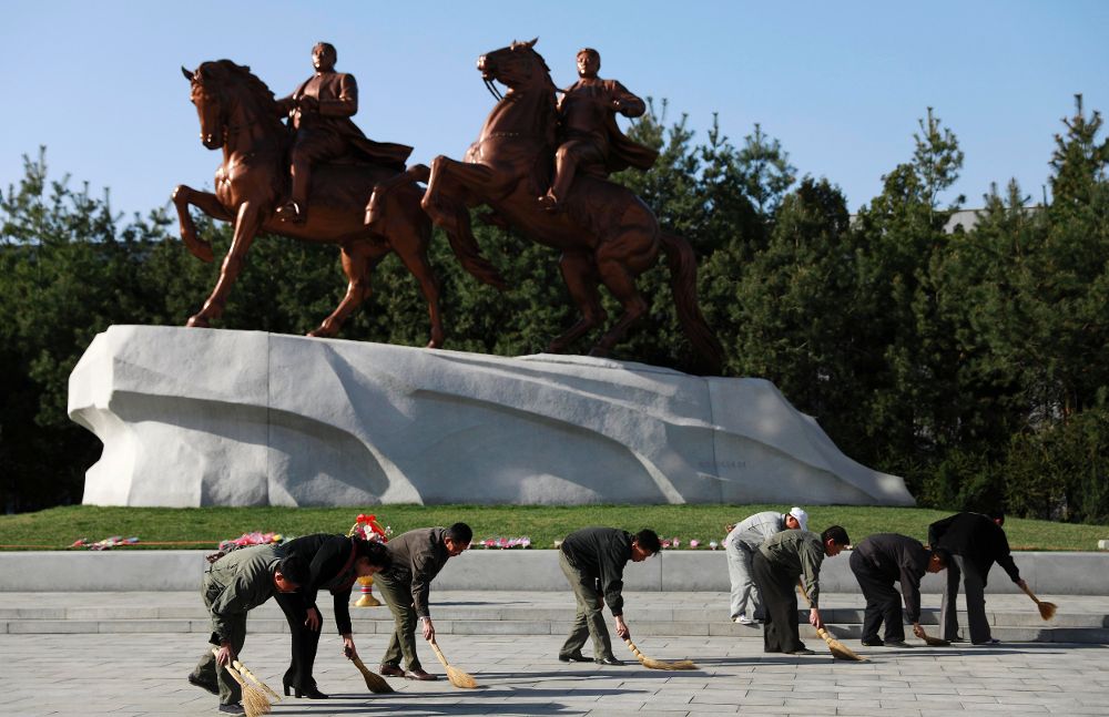 Trabajadores norcoreanos limpian el suelo frente a una estatua del fundador de su país, Kim Il-sung, y el "querido líder" Kim Jong-il junto a la Galería de Arte Mansudae en Pyongyang (Corea del Norte).