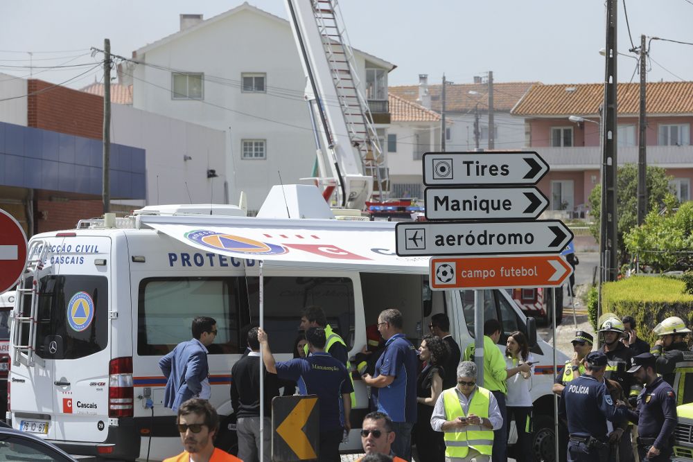 Bomberos trabajan en las labores de extinción de varios edificios en llamas tras estrellarse una avioneta junto a un supermercado en Tires, cerca de Estoril.