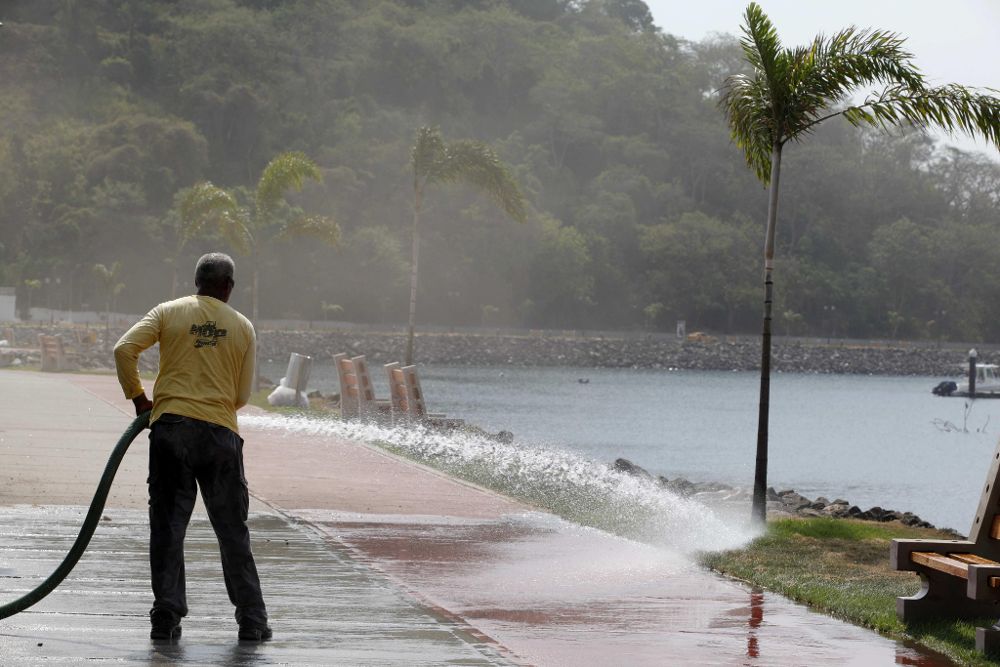 Un trabajador esparce agua en el pasto de un área turística de la ciudad de Panamá por la ola de calor sobre Centroamérica de finales de marzo y principios de abril.