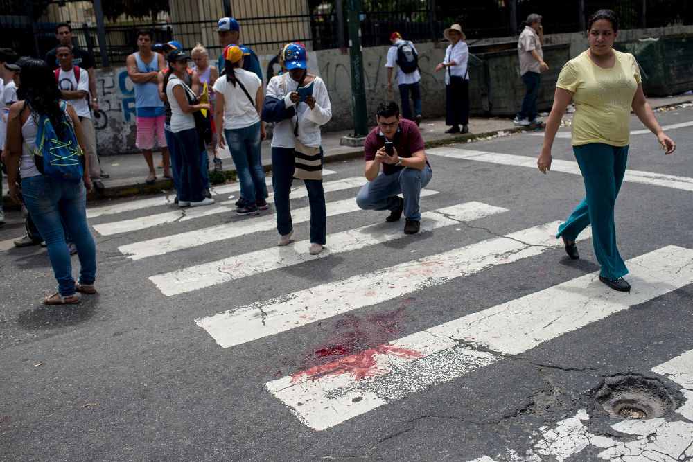 Vista de la mancha de sangre del joven de 17 años que recibió un disparo durante una concentración de la oposición hoy, miércoles, en Caracas.