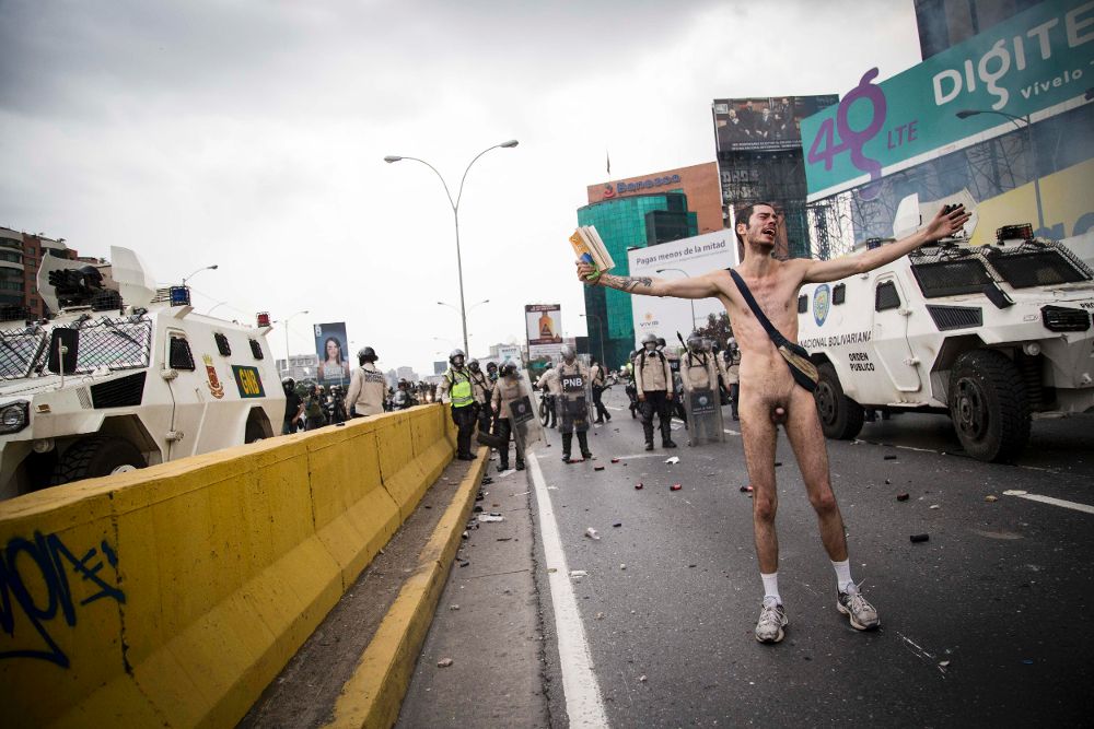 Un hombre protesta desnudo en Caracas, ayer, jueves. Grupos de centenares de opositores al Gobierno venezolano se enfrentaron con las fuerzas de seguridad en diversos sectores del este de la capital.