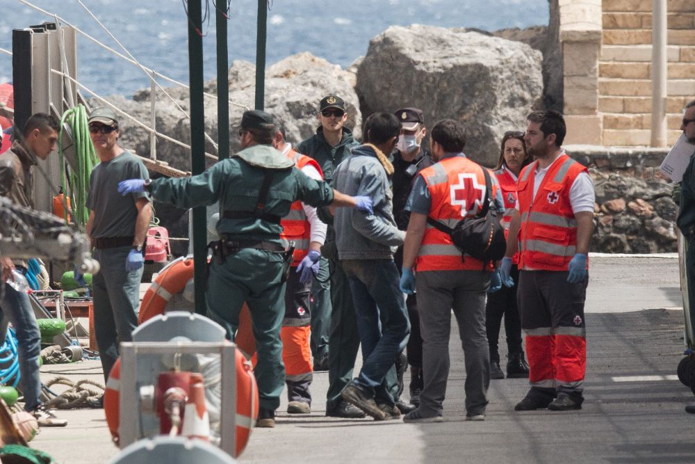 Agentes de la Guardia Civil y personal de Cruz Roja ayudan a bajar de la embarcación de Salvamar Denébola a 18 varones de origen magrebí que han sido rescatados por Salvamento Marítimo a 8 millas naúticas al sur de Almerimar.