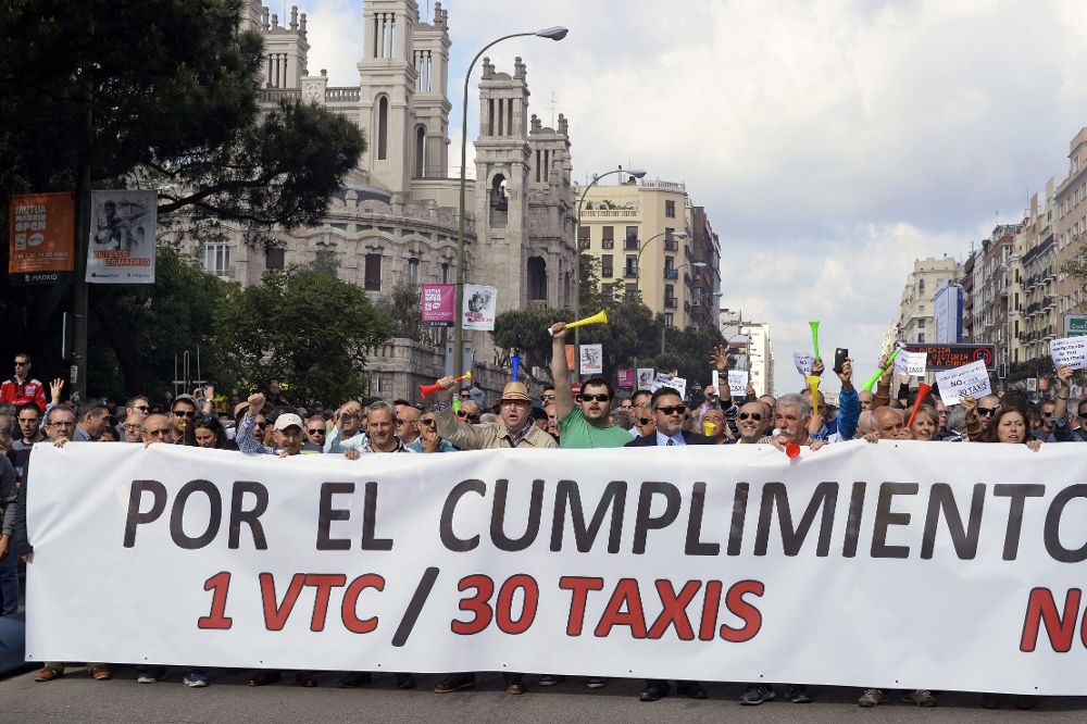 Decenas de taxistas portan una pancarta durante la manifestación de hoy en la madrileña calle Raimundo Fernández Villaverde.