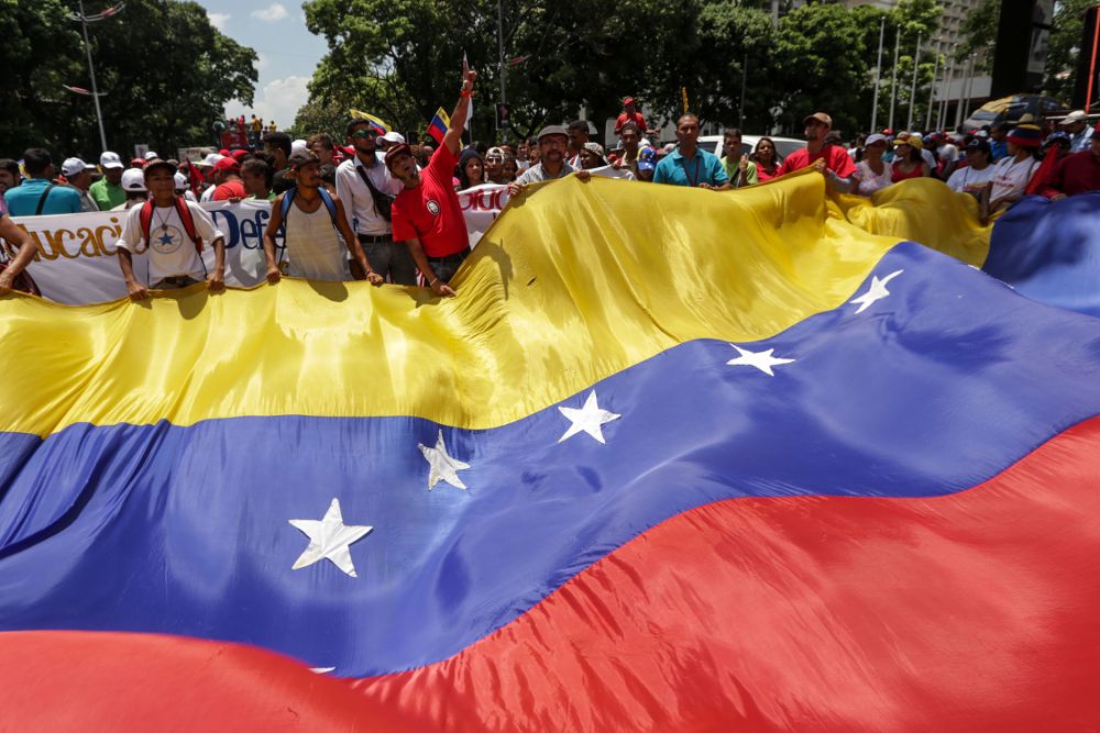 Simpatizantes del chavismo ondean una bandera gigante de Venezuela durante una manifestación.