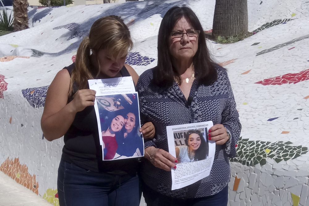 La madre (d) de María Jimena Rico muestra junto a una amiga las fotografías de ambas jóvenes horas antes de haber sido localizadas.