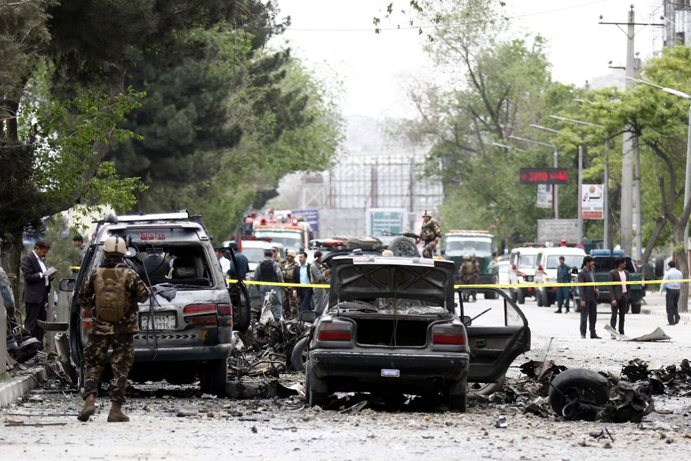 Miembros de las Fuerzas de Seguridad afganas inspeccionan el lugar donde se ha producido un atentado suicida con bomba al paso de un convoy de la misión de la OTAN en Kabul.