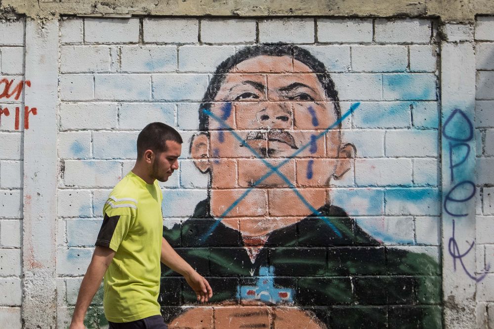 Un hombre camina frente a una pared con un dibujo del fallecido presidente de Venezuela Hugo Chavez en Caracas (Venezuela). 