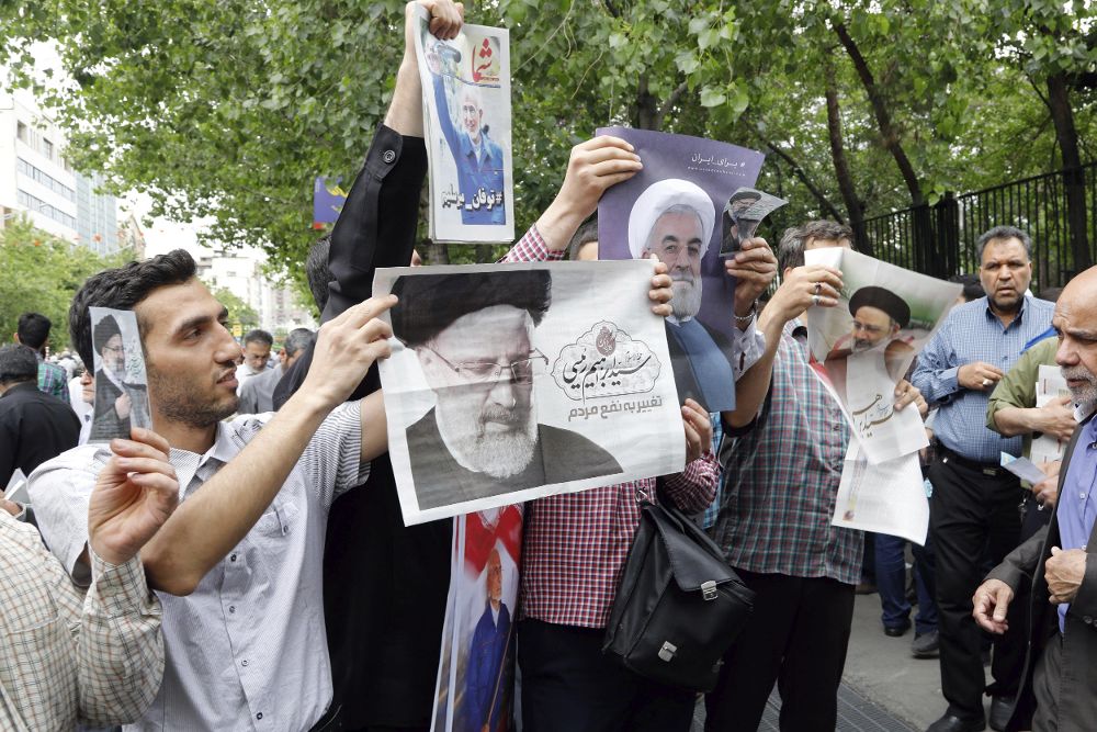 Ciudadanos muestran carteles electorales de los candidatos a las elecciones presidenciales iraníes Hasán Rohaní y Ebrahim Raisí.