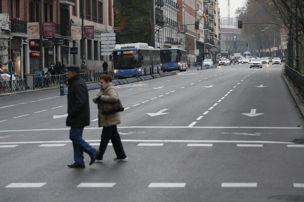 Dos peatones cruzan la calzada en el Paseo del Prado de Madrid