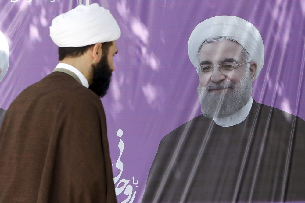 Una clérigo iraní observa un cartel electoral del actual presidente iraní, Hasan Rohaní.
