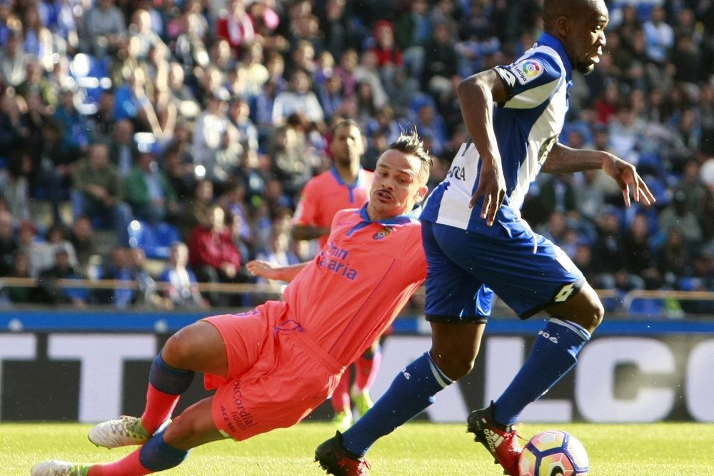El delantero liberariano del Deportivo Ola John (d) disputa el balón con el centrocampista Roque Mesa (i), de la UD Las Palmas.