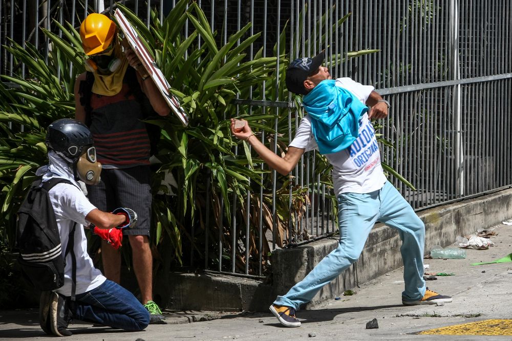 Manifestantes opositores se enfrentan a integrantes de la Guardia Nacional Bolivariana durante una marcha en contra del gobierno venezolano ayer, viernes, en Caracas.