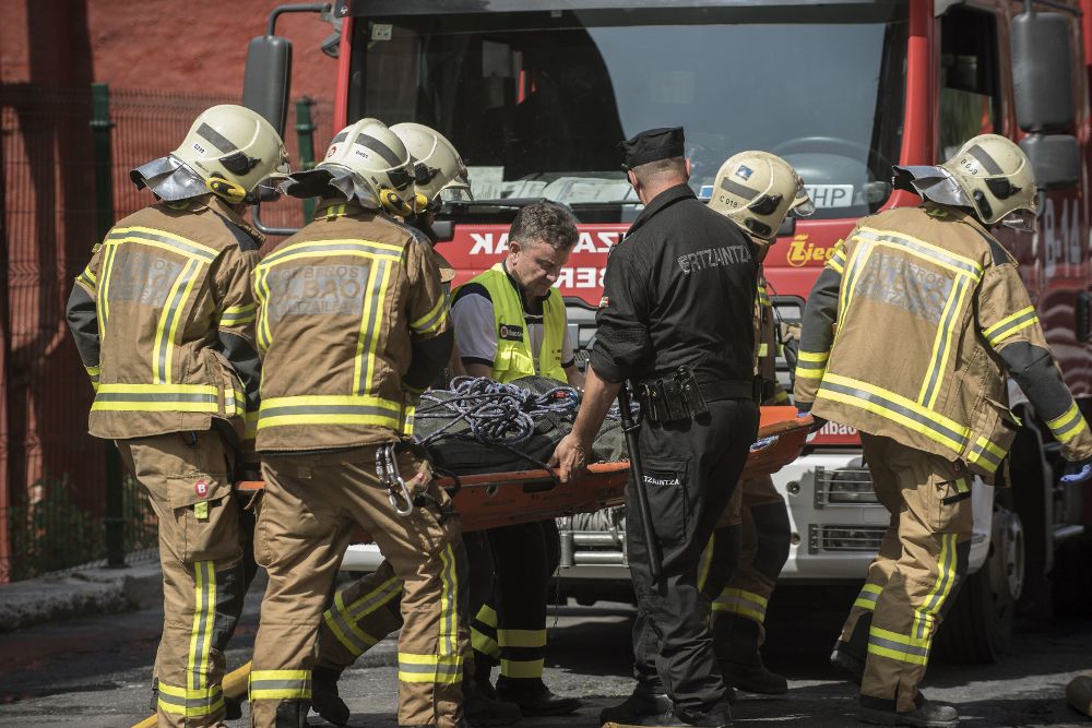 Los servicios de emergencia evacuan el cuerpo de uno de los cuatro fallecidos en el incendio de la vivienda declarado esta mañana en el barrio bilbaíno de Zorroza. 