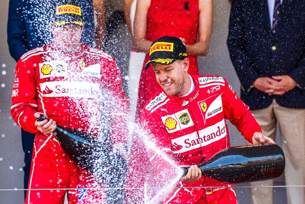 Sebastian Vettel (d) celebra su victoria en el podium con su compañero de escudería detrás.