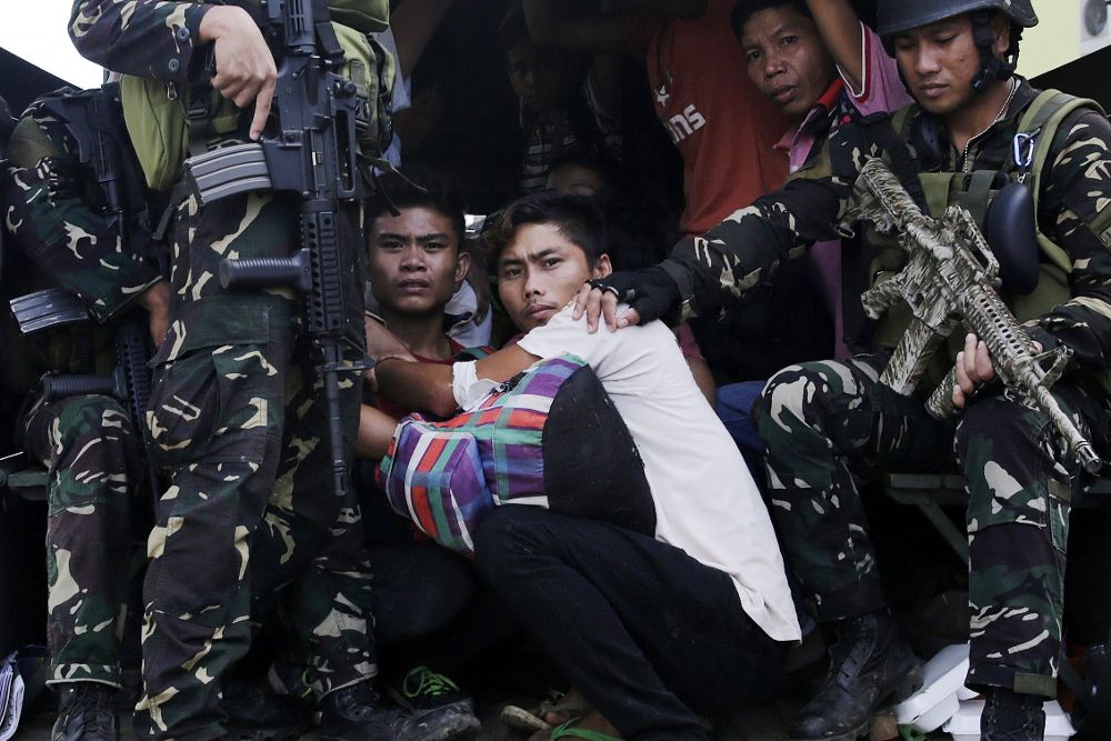 Filipinos que quedaron atrapados en medio de los enfrentamientos entre militantes islamistas y las Fuerzas del Gobierno son custodiados por soldados filipinos.