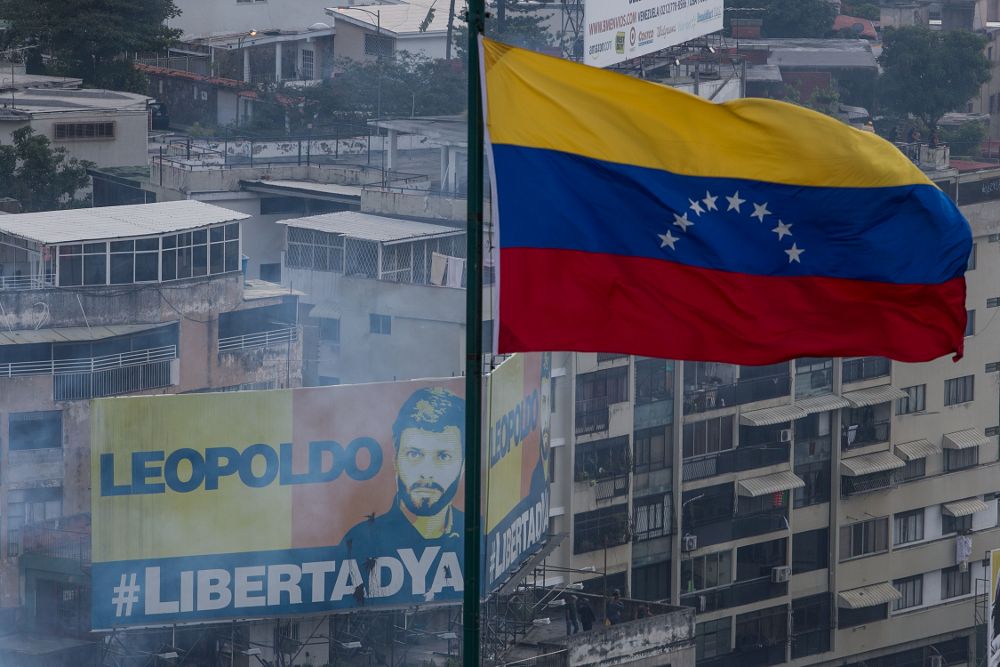 Una bandera de Venezuela ondea frente a un retrato del líder político opositor encarcelado Leopoldo López en Caracas.