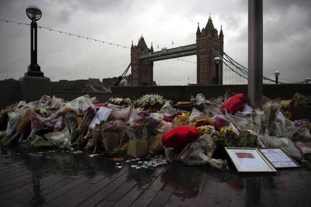 Varios ramos de flores, velas y mensajes dejados en memoria de las víctimas en los alrededores del Ayuntamiento de Londres.