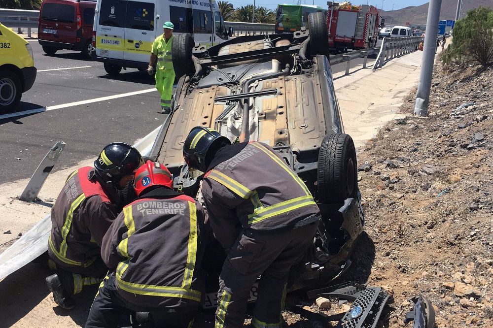 Los bomberos del parque de Santa Cruz de Tenerife tratando de liberar a tres ocupantes de un vehículo volcado en la autopista TF-1 a la altura del municipio de Arafo. 
