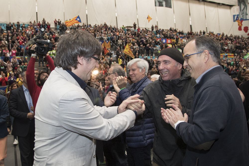 El presidente de la Generalitat, Carles Puigdemont (i), saluda a Lluis Llach (c) en presencia de Jordi Turull (d) en una fotografía retrospectiva.