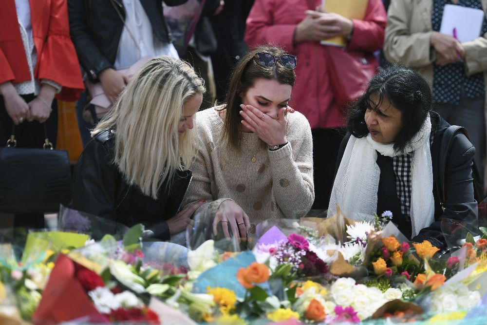 Una mujer llora mientras contempla las flores colocadas como homenaje a las víctimas del atentado terrorista en la capital británica.