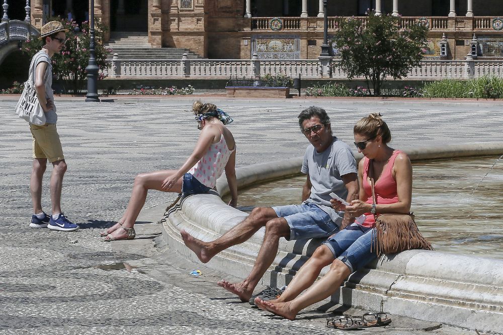 Turistas se refrescan en la plaza de España en Sevilla.
