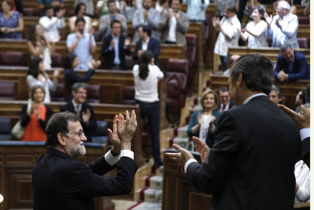 El presidente del Gobierno, Mariano Rajoy (i), junto al portavoz parlamentario del PP, Rafael Hernando, aplaude con la bancada popular tras la votación.