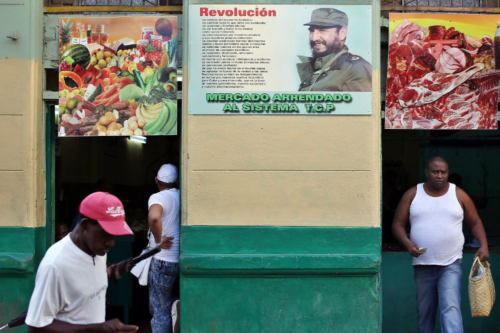 Varias personas caminan junto a un cartel con la imagen del fallecido líder cubano Fidel Castro el martes 13 de junio, en La Habana.