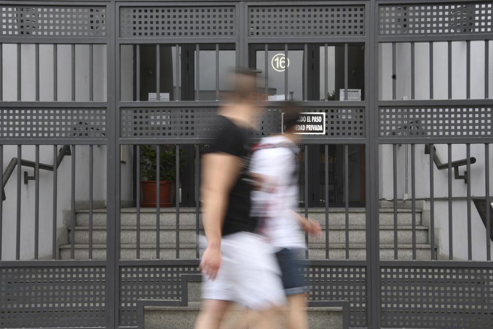 Dos jóvenes pasan por delante del domicilio de Segovia donde la Policía detuvo a Pedro Luis Gallego.