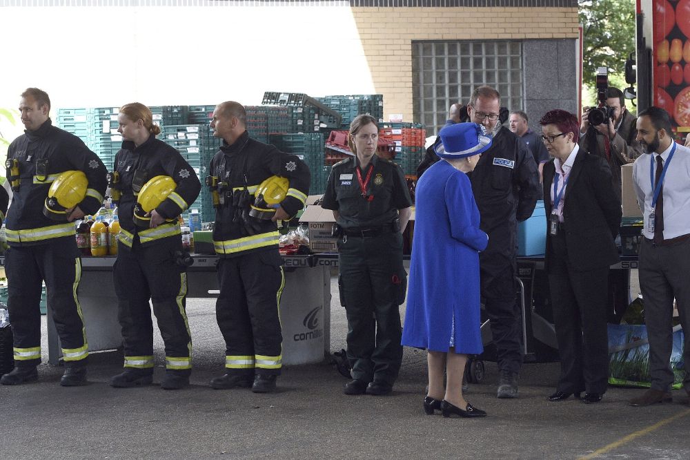 La reina Isabel II saluda a trabajadores del Servicio Nacional de Salud (NHS) durante una reunión con residentes de la torre Grenfell.