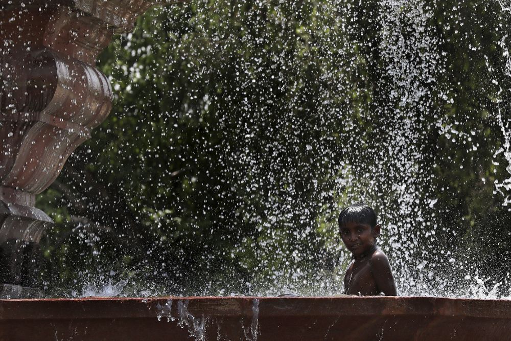 Un niño se baña en una fuente en Nueva Delhi (India) el 9 de mayo. Los termómetros marcaron hasta 44 grados en la capital india debido a una fuerte ola de calor.