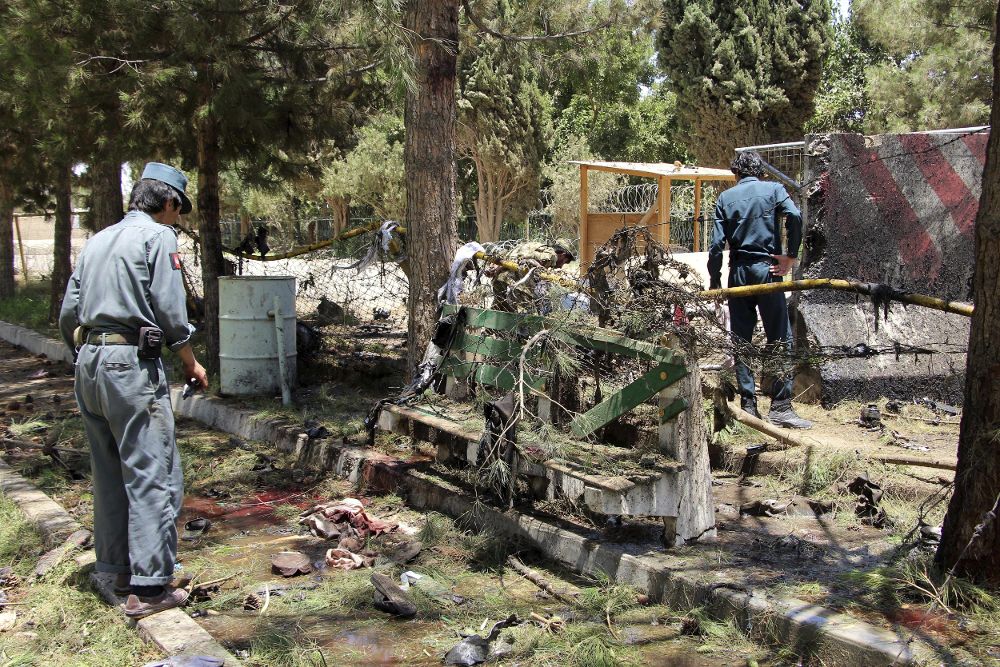 Agentes de seguridad afganos inspeccionan el lugar donde se produjo un atentado suicida con un coche cargado de explosivos en la entrada de una sucursal bancaria, en Lashkargh, provincia de Helmand.