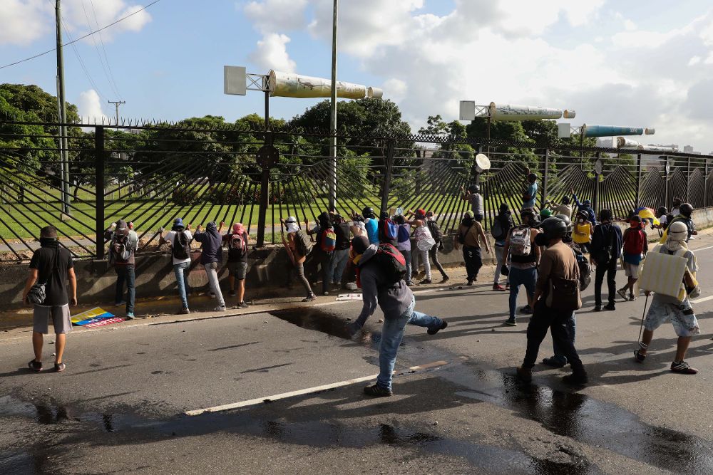 Manifestantes destruyen una reja hoy, ayer, jueves, durante una nueva jornada de protestas en Caracas.