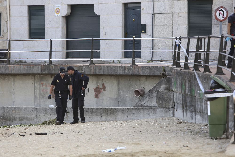 Dos agentes de la Policia Nacional investigan en la playa donde se produjo el homicidio.