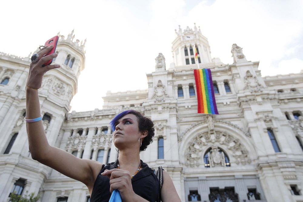 Una mujer se fotografía junto a la fachada del Ayuntamiento de Madrid donde se ha desplegado la bandera del orgullo gay con motivo de la celebración del World Pride 2017.