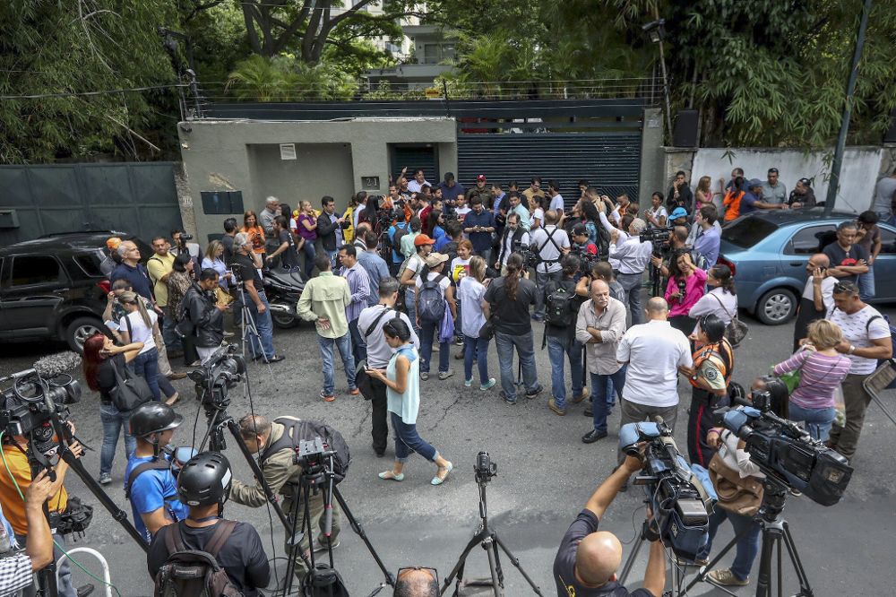 Familiares y militantes del partido Voluntad Popular, junto a miembros del Servicio Bolivariano de Inteligencia Nacional (Sebin) y periodistas, permanecen en la entrada de la casa en Caracas del opositor venezolano Leopoldo López que ha abandonado la cárcel y ha pasado a estar en una situación de "arresto domiciliario".