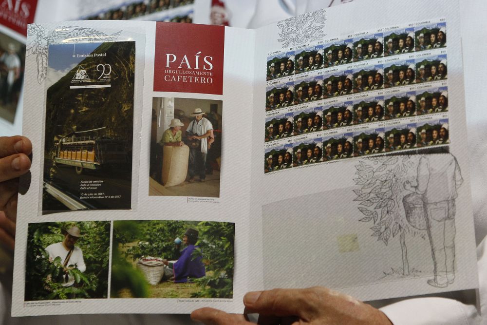 Un hombre muestra la emisión filatélica en conmemoración a los 90 años de la Federación Nacional de Cafeteros de Colombia.