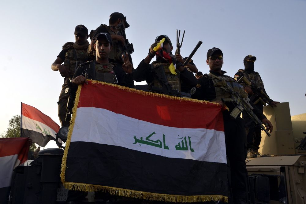 Soldados iraquíes sostienen una bandera iraquí en el centro de Mosul (Irak).