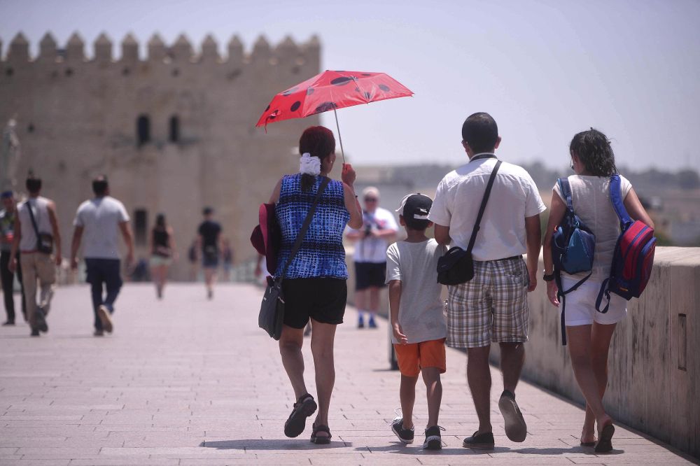 Turistas pasean por el Puente Romano de Córdoba, hoy en el que aún se mantiene activada la alerta por calor en riesgo extremo.