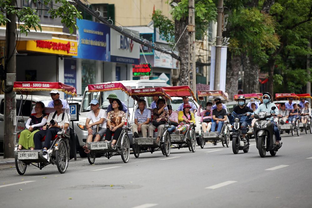 Bicitaxistas pasean a los turistas por un calle en Hanoi (Vietnam).