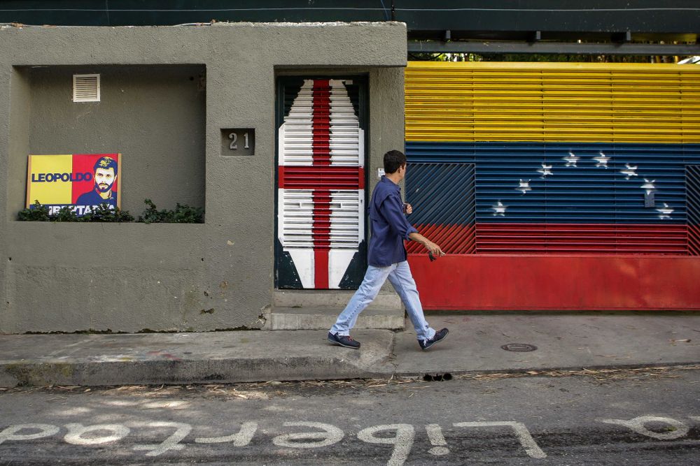 Un hombre pasa frente a la casa del líder opositor Leopoldo López después de ser recluido en una celda de la cárcel militar de Ramo Verde, a las afueras de Caracas, junto al alcalde Antonio Ledezma.