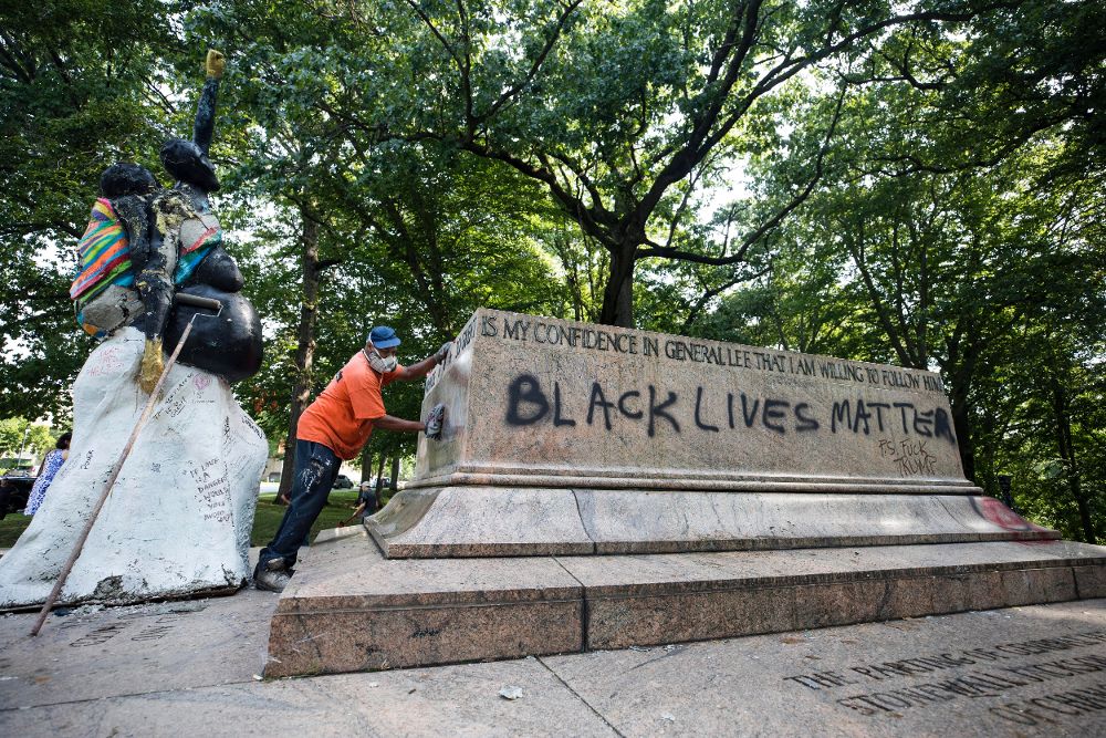 Un trabajador limpia un grafiti de la base del Monumento de Robert E. Lee y Stonewall Jackson, una de las estatuas que conmemoraba la época de la Confederación después de que unos trabajadores quitaran la estatua durante la noche en el parque Wyman, en Maryland.