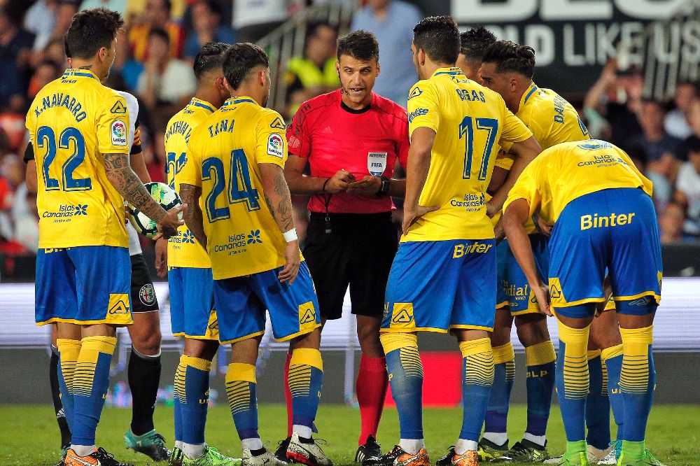 Los jugadores de la UD Las Palmas reclaman una acción al árbitro Jesús Gil Manzano (c) durante el partido de la primera jornada de Liga de Primera División que Valencia y UD Las Palmas juegan esta noche en el estadio de Mestalla, en Valencia.