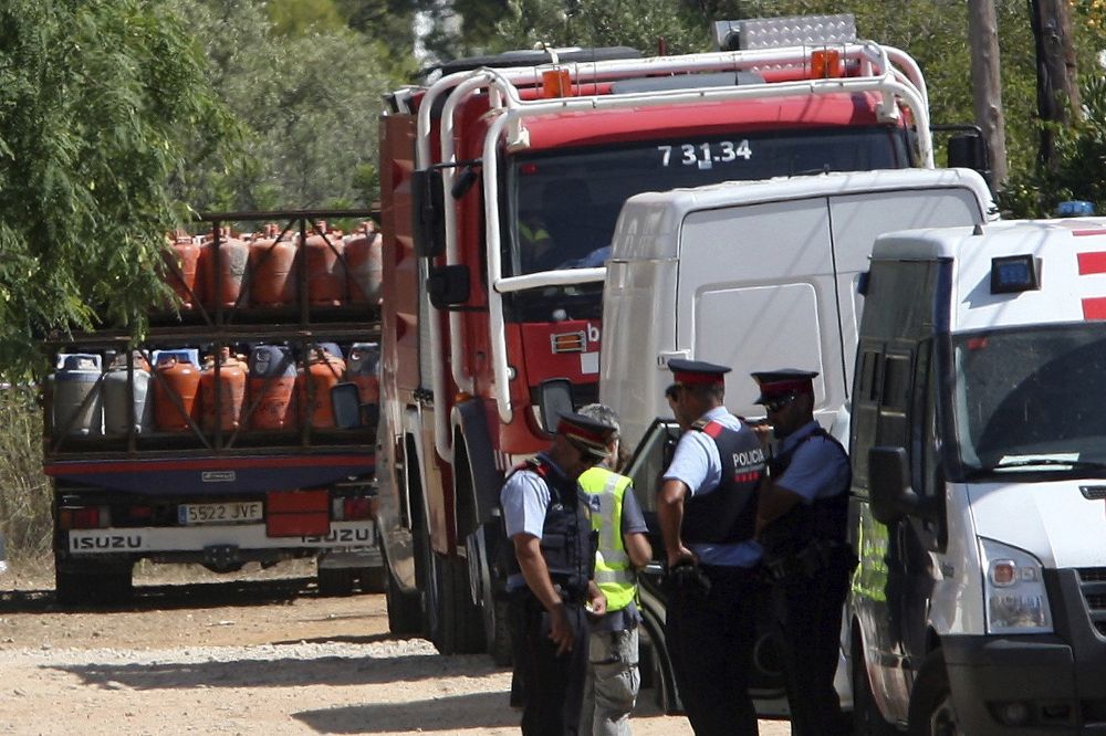 Un camión (i) retira parte de las 120 bombonas de butano halladas en el chalet de Alcanar Platja utilizado por los terroristas de Barcelona y Cambrils como base operativa.