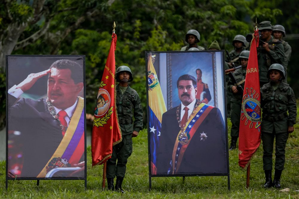 Militares venezolanos posan junto a los retratos de Hugo Chávez (i) y Nicolás Maduro.