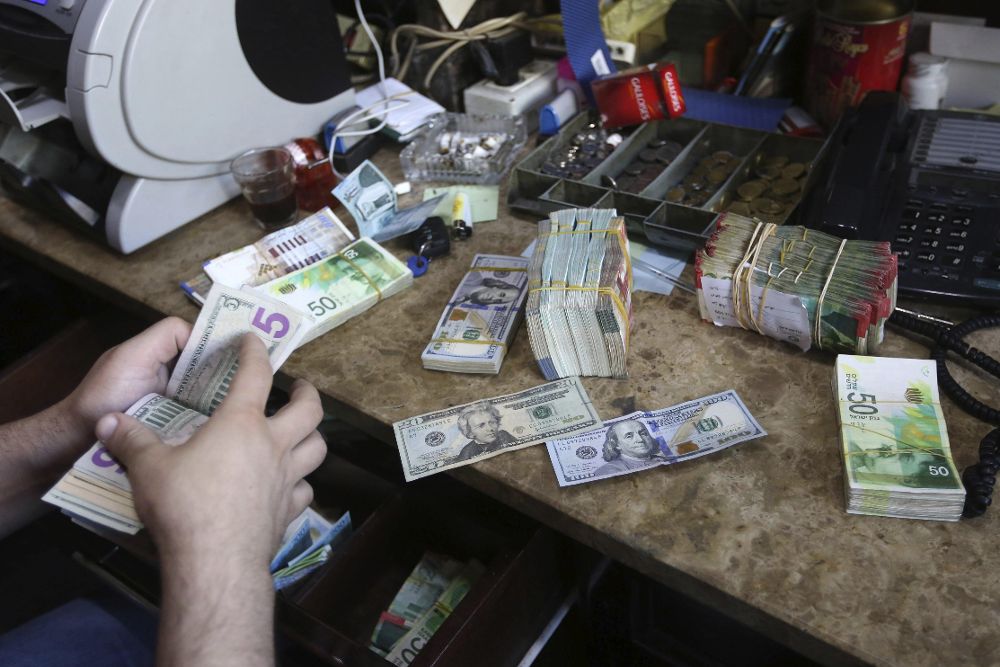 Un trabajador cuenta billetes de dólar en una tienda de intercambio de valores de Nablus (Palestina) hoy, 29 de agosto.