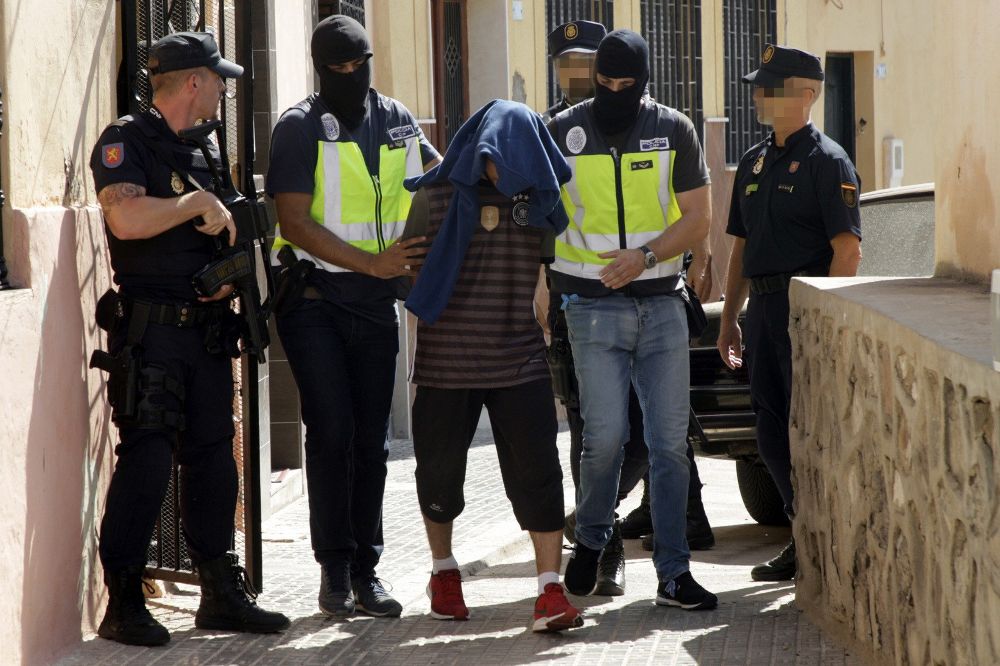 Efectivos de la Policía Nacional traslada a una persona detenida durante el registro realizado hoy en un domicilio del barrio periférico del Monte María Cristina de Melilla.