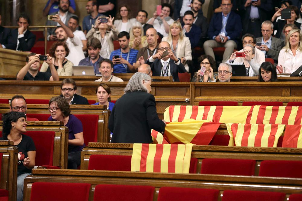 La diputada de Cataluña si que es pot, Angels Martínez retira las banderas de España de los escaños del PPC.